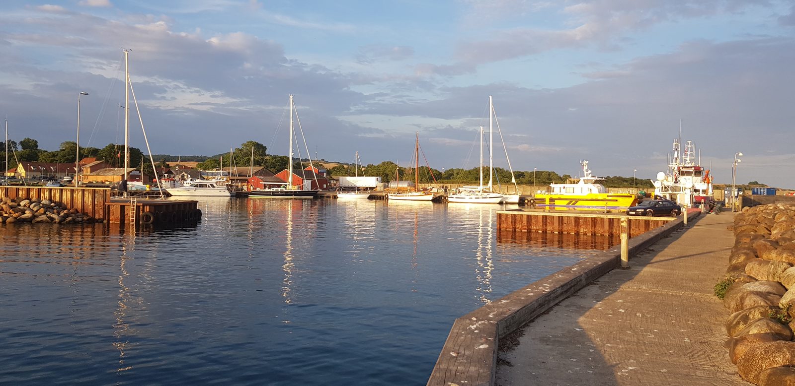 Fishing harbour and marina of Klintholm Havn in evening light with quay and boats