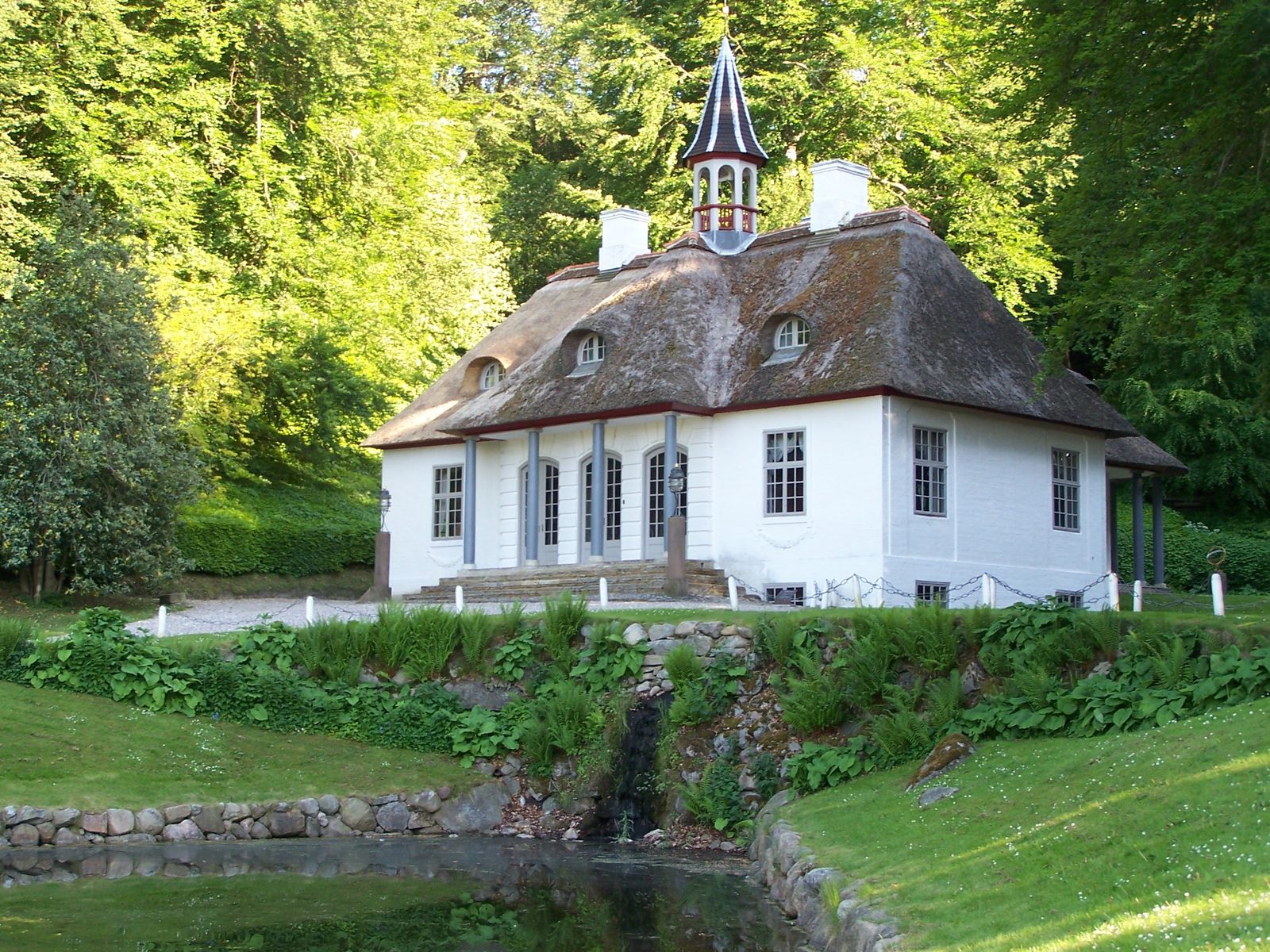 The white, thatched Liselund manor with its small tower above the pond in the park