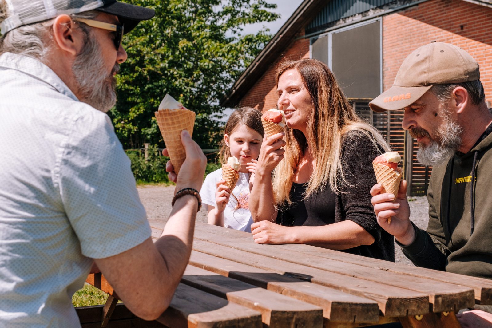 Family eating ice cream cones at a wooden table at the Møn Is farm