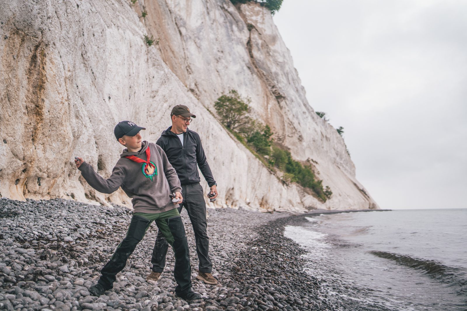 Father and son skipping stones on the beach below Møns Klint