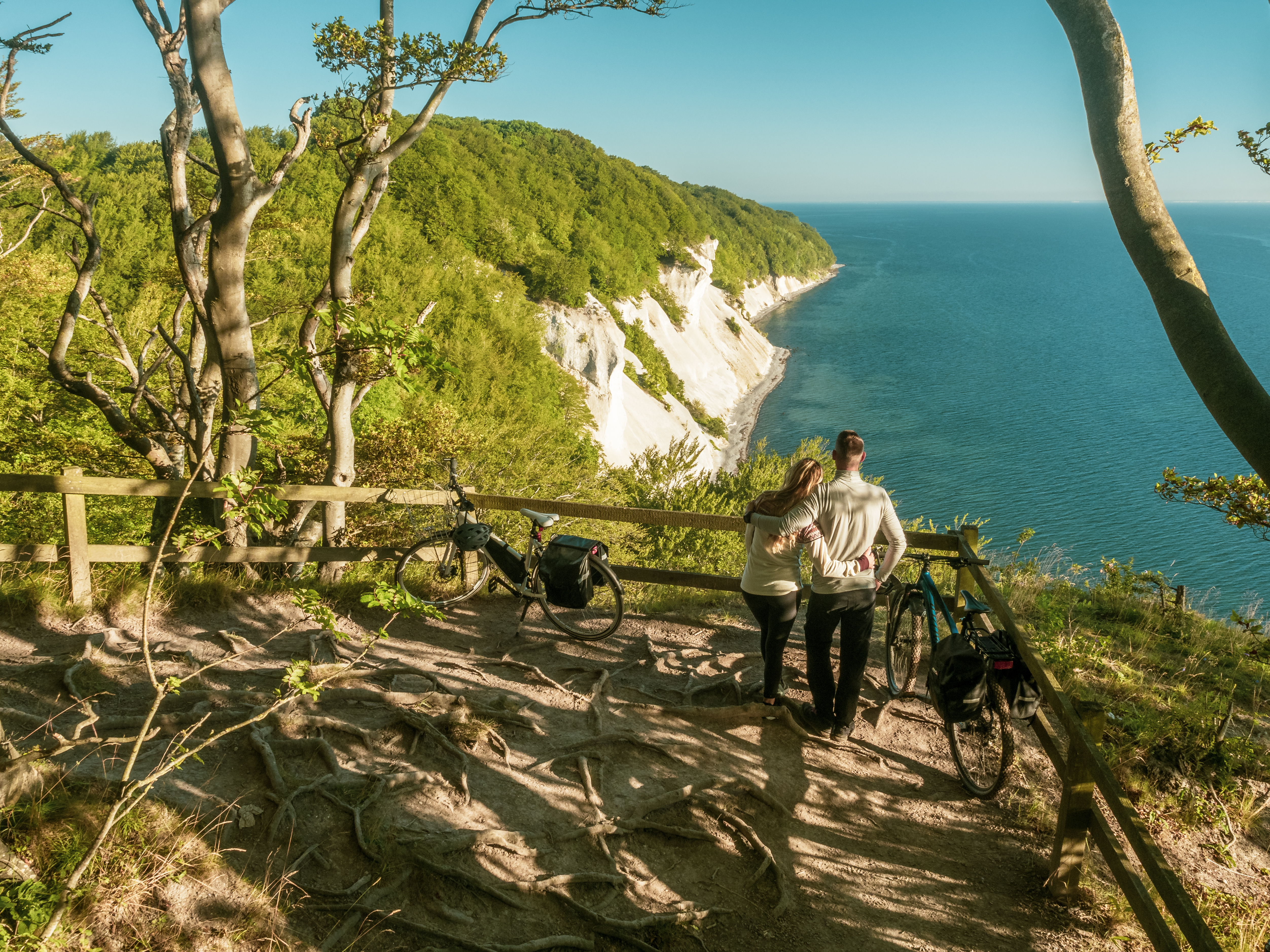 Two bicycles at a viewpoint above the chalk cliffs of Møns Klint, in front a couple looking out over the Baltic Sea